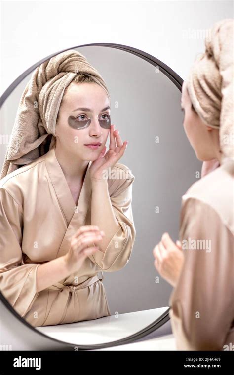 A Well Groomed Woman At Home In A Bathrobe And Towel Applies Patches