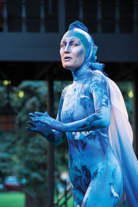 A Woman With Blue Paint On Her Face And Body Is Standing In Front Of A