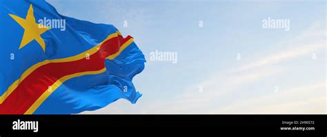 Official Flag Of Congo Kinshasa At Cloudy Sky Background On Sunset