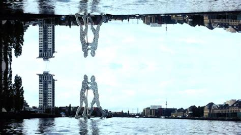 The Reflection Of Two People Walking In Water