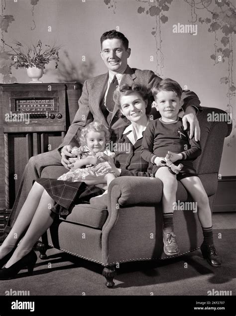 1940S GLÜCKLICH LÄCHELNDE FAMILIE VON VIER SITZEN ZUSAMMEN IM