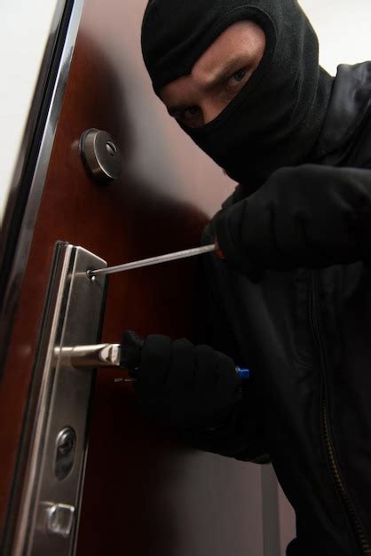 Premium Photo Male Burglar In Mask Breaking Into The House
