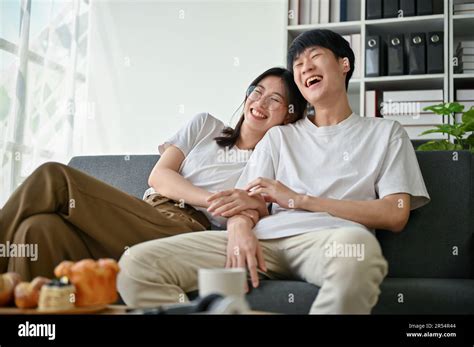 A Cute Young Asian Girlfriend Is Hugging And Laughing With Her Boyfriend While Enjoying Watching