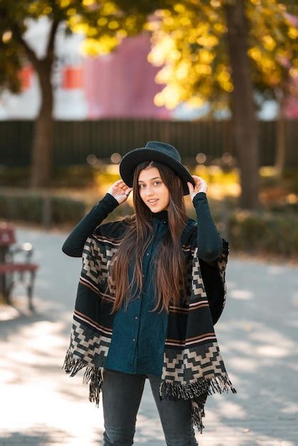 Premium Photo Stylish Woman In Poncho And Hat Enjoys Autumns Park
