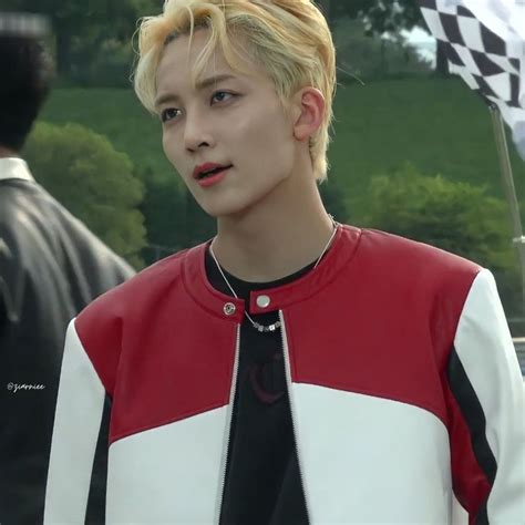 A Man With Blonde Hair Wearing A Red White And Black Jacket Standing