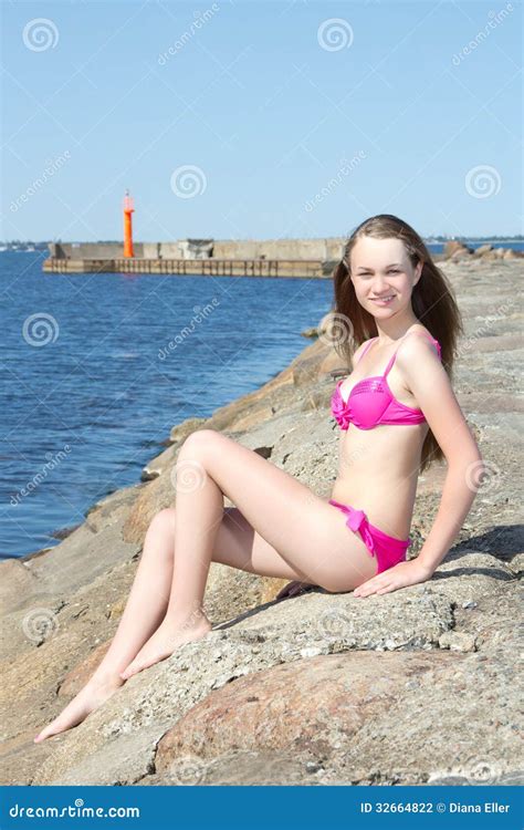 Modelo Atractivo En El Bikini Rosado Que Se Sienta En La Playa Rocosa Foto De Archivo Imagen