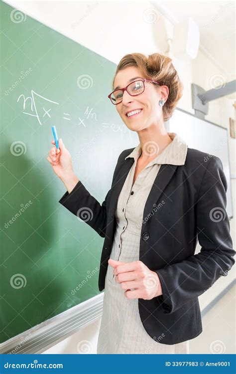 Teacher Writing With Chalk In Front Of School Class On Board Stock