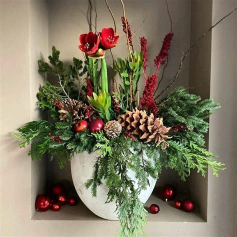 A White Vase Filled With Lots Of Greenery And Red Berries On Top Of A Shelf