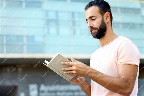 Premium Photo Handsome Pensive Bearded Man Reading Book Standing On