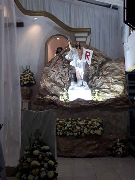 A Statue Of Jesus On Top Of A Rock In A Room With Flowers And Curtains