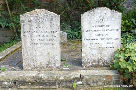 Two Headstones Are Sitting On The Ground In Front Of Some Bushes And Trees