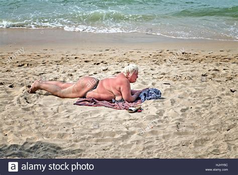 Obese And Overweight Woman Wearing A Bikini And Sunbathing On The Beach