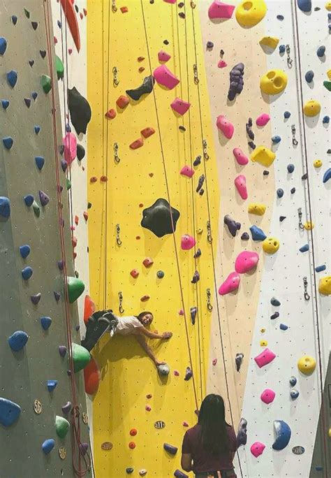 Two People Climbing Up The Side Of A Wall With Colorful Rock Climbing