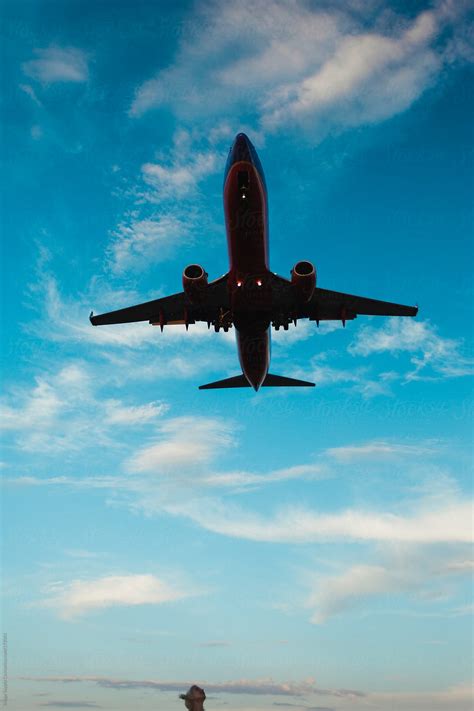 Tiny Head Looking Up At Massive Airplane In The Sky By Stocksy