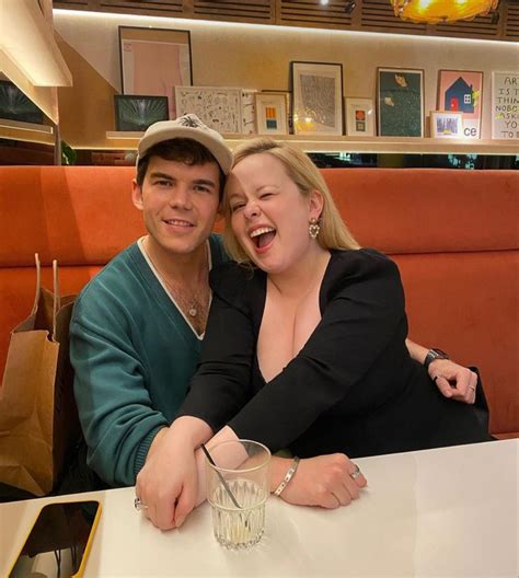 A Man And Woman Sitting At A Table In A Restaurant With Their Arms