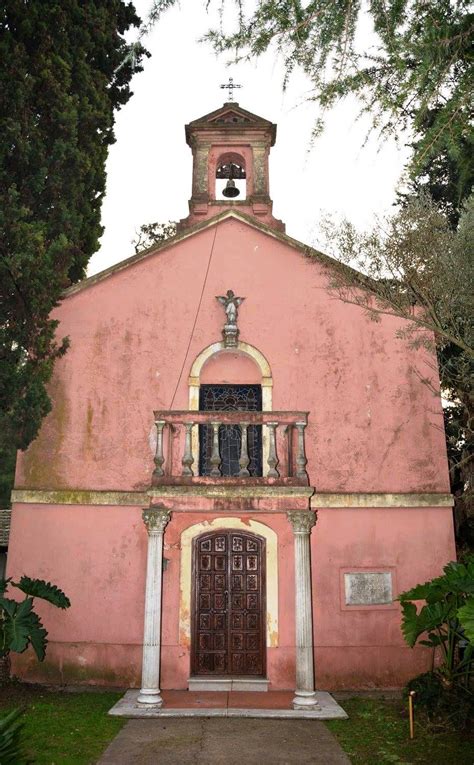 An Old Pink Building With A Bell Tower On It S Roof And Two Doors