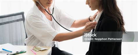 Senior Female Doctor Using Stethoscope Listening To Patients Heartbeat In Hospital Medical