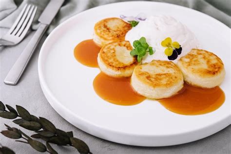 Panqueques De Cuajada Con Crema Agria Y Mermelada En Un Plato Blanco