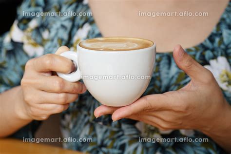 women hands holding hot cup of coffee or tea in morning sunlightの写真素材