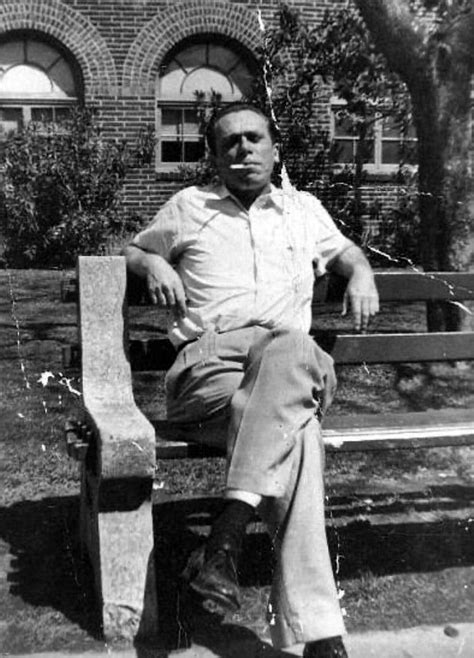 Black And White Photograph Of Man Sitting On Bench In Front Of Brick