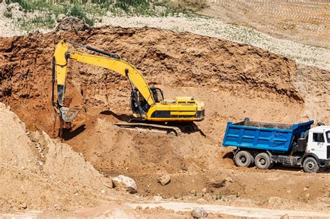 Premium Photo An Excavator In A Sand Pit Loads A Dump Truck With Sand