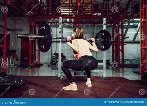 Gorgeous Young Fitness Woman Crouch And Doing Squad Exercise With A Bar