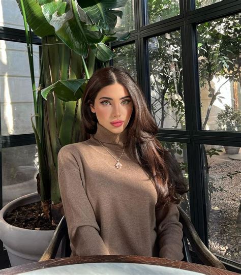 A Woman Sitting In Front Of A Window Next To A Potted Plant And Looking