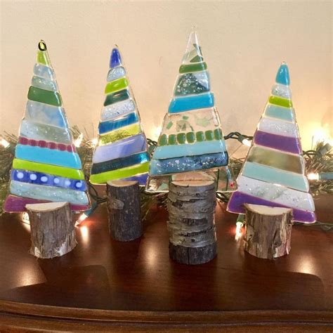 Three Colorful Glass Trees Sitting On Top Of A Wooden Table