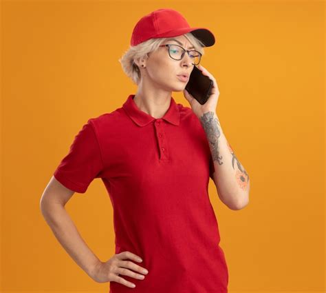 Repartidor Joven En Uniforme Rojo Y Gorra Con Gafas Hablando Por