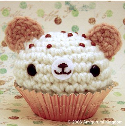 A Crocheted Teddy Bear Sitting Inside Of A Cupcake On Top Of A Table