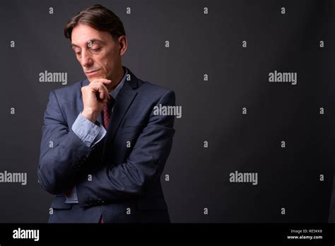 Mature Handsome Italian Businessman Thinking Against Gray Background