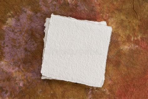 Small Square Sheet Of Blank White Paper Against Colorful Marbled Paper