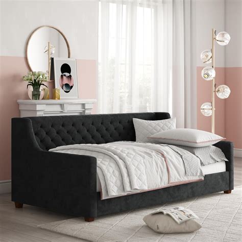 a bedroom with pink and white walls, a black sofa bed and a mirror on ...