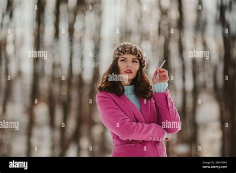 A Shallow Focus Of A Cool Brunette Woman Wearing A Pink Coat Smoking A Cigarette Outside In