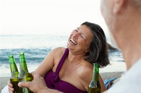 Free Photo Senior Man And Woman Laughing On The Beach While Having Beer