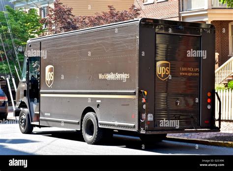 A Ups Truck Parked On The Street While The Driver Makes A Delivery