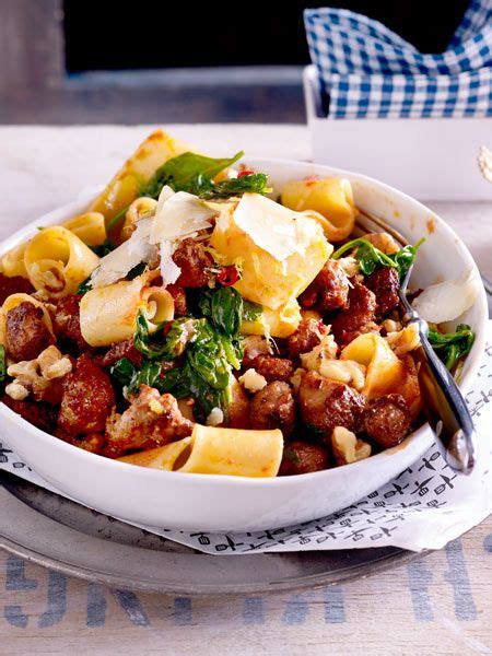 A White Bowl Filled With Pasta And Meat On Top Of A Table Next To A Fork