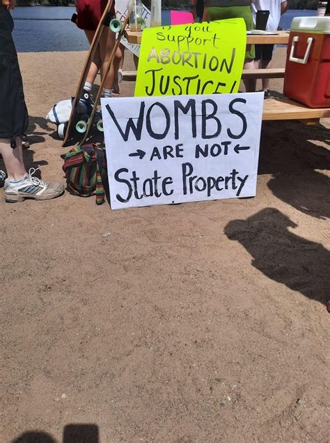 A Sign That Is Sitting On The Ground In Front Of A Table With People