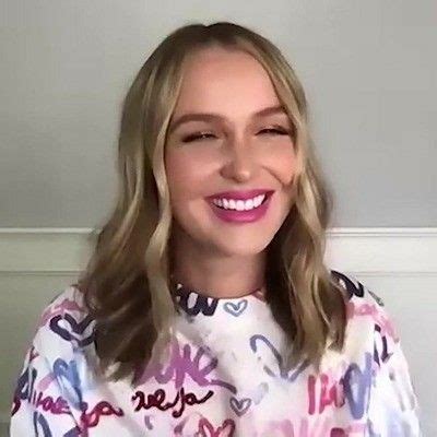 A Woman With Blonde Hair Wearing A White Shirt And Pink Lipstick