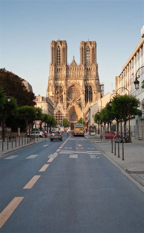 An Empty Street With Cars Parked On Both Sides And Large Cathedral In