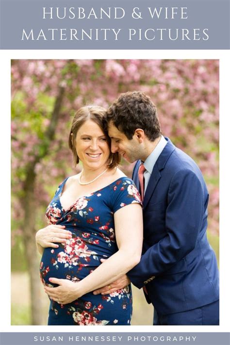 A Pregnant Couple Embracing Each Other In Front Of Pink Flowers With