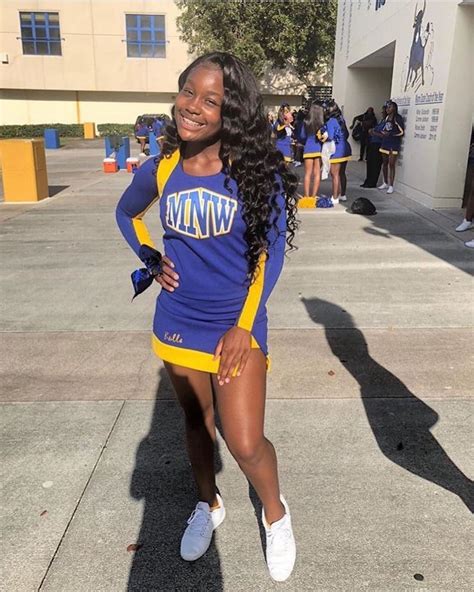 a woman in a cheerleader uniform poses for a photo on the side walk ...