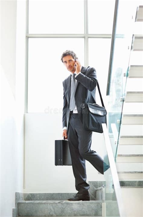 Mature Executive Carrying Bags And Talking On Cellphone Full Length Of