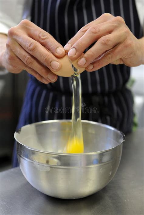 Cozinheiro Chefe Da Mulher Que Quebra O Ovo Na Bacia Foto De Stock