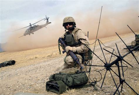 Man In Brown Military Uniform Holding M4a1 While Sitting On Floor