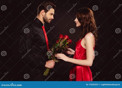 Side View Of Handsome Man Giving Roses To Attractive Girlfriend Stock