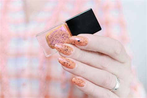 Female Hand With Long Nails And A Yellow Orange Nail Polish Stock Image