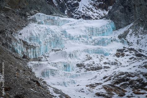 Glacier From Blue And White Ice Lies At The Foot Of Mountains In