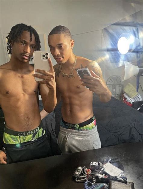 Two Men Standing In Front Of A Mirror Taking A Selfie With Their Cell