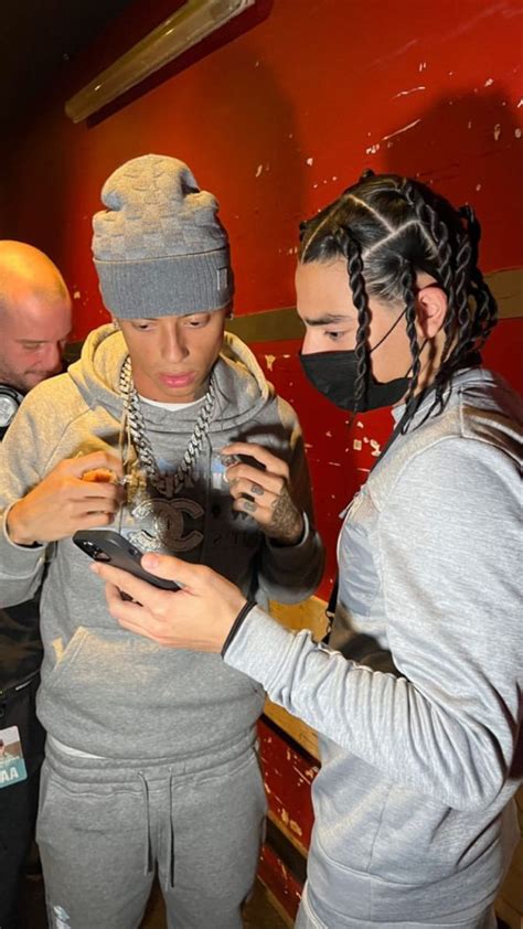 Two People Wearing Face Masks Looking At Their Cell Phones While